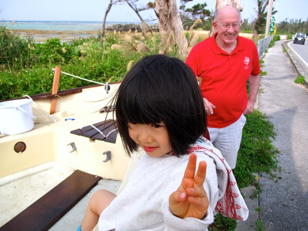 A little girl comes by and wants to sit in the boat.